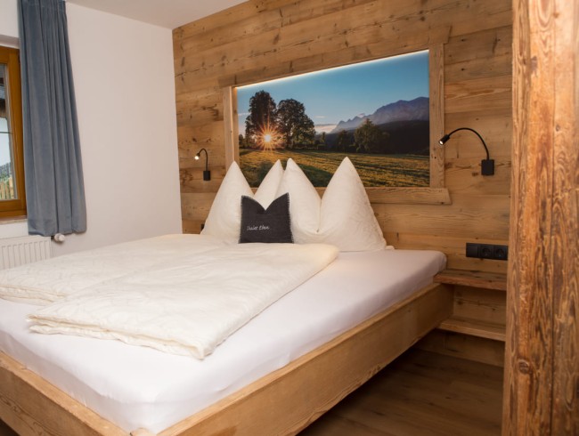 Schlafzimmer mit Altholz und Lodenkissen